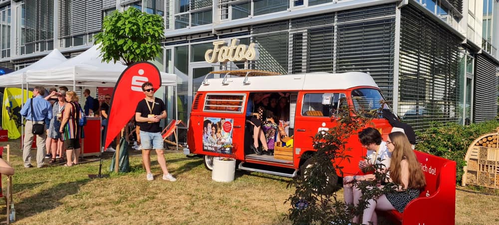 Gäste am roten Foto Bulli auf einem Firmen-Sommerfest